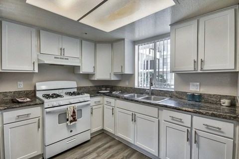 a kitchen with white cabinets and a stove and a sink